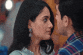 a man and a woman are kissing and the woman has earrings on her ear