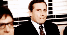 a man in a suit and tie is sitting in front of a window .