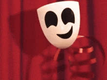 a white mask with a face drawn on it is on a red curtain