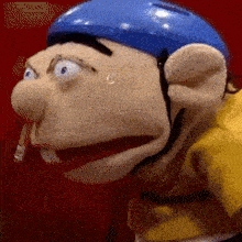 a close up of a puppet wearing a blue helmet and smoking a cigarette