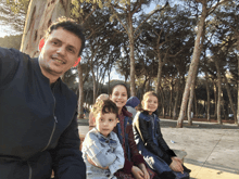 a man and three children pose for a picture in front of a forest