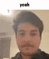 a man with a mustache is looking at the camera with the words `` yeah '' behind him .