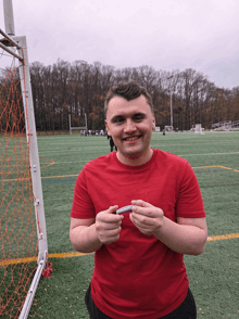 a man in a red shirt holds a small object in his hand
