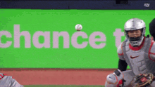 a catcher catches a ball in front of a green sign that says " chance "