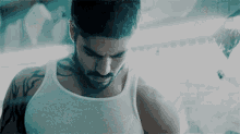 a man in a white tank top has a tattoo on his left arm