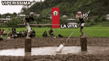 two people are standing on stump in a muddy field with a sign that says la vita .