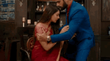 a man in a blue suit holds the hand of a woman in a red sari