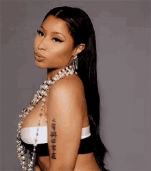 a woman with a tattoo on her arm wearing a pearl necklace and earrings .