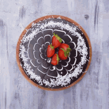 a chocolate cake with strawberries and coconut shavings on top