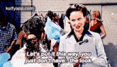 a woman in a white coat is talking to another woman in front of a clothes rack .