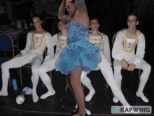 a group of men are sitting in chairs and one of them is wearing a blue dress and the caption says kapwing