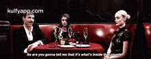 a man and two women are sitting at a table in a restaurant talking to each other