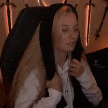 a woman wearing a white shirt and a black hoodie is sitting in a chair with her eyes closed