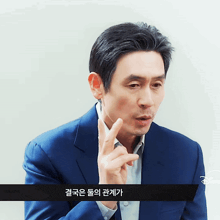 a man in a blue suit has a foreign language written on the bottom of the screen