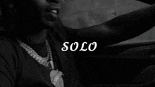 a black and white photo of a man driving a car with the word solo written on the bottom
