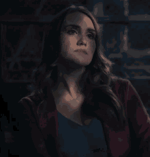 a woman wearing a red jacket and a blue shirt looks up