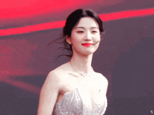 a woman wearing a white dress and a necklace stands in front of a red background