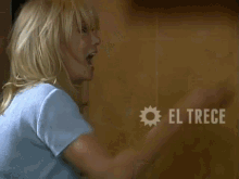 a woman in a blue shirt is screaming with el trece in the corner