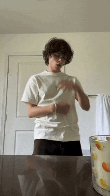 a young man in a white t-shirt is standing in front of a door