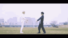 two people standing in a grassy field holding hands