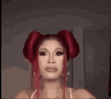 a drag queen with red hair and pigtails is looking at the camera .