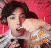 a man wearing headphones is eating something with a spoon while wearing a shirt that says i am hungry