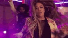 a woman with purple hair is dancing in a club with her hands in the air .