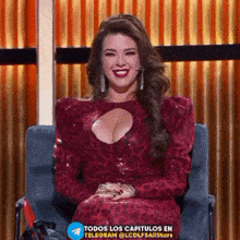 a woman in a red dress is sitting in a chair and smiling