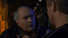 a man is talking to another man in a dark room in a movie .