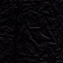 a piece of crumpled black paper with a cross in the middle