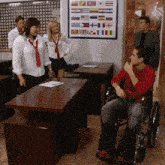 a man in a wheelchair talks to a group of people