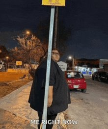 a man standing next to a pole with the words me right now below him