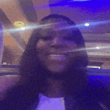 a woman is smiling in front of a purple background