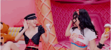 two women are standing next to each other holding ice cream cones in front of a large ice cream cone .