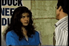 a man and a woman are talking in front of a sign that says duck nee du