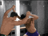 two men are fighting in a locker room with lockers behind them
