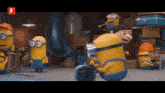 a group of minions are gathered in a room with the letter b on the bottom right