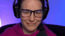 a woman wearing glasses and headphones is smiling and looking at the camera .