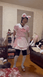 a man in a pink maid costume is standing in a living room