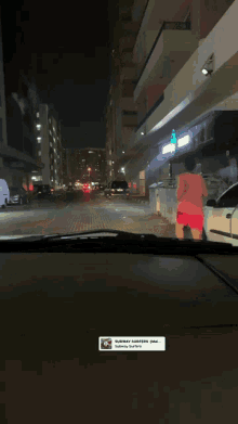 a man in a red shirt is running down a city street