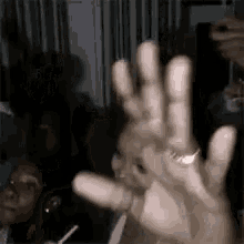 a close up of a person 's hand waving in front of a group of people .
