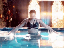 a woman in a black bikini is swimming in a pool