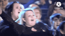 a group of people are sitting in a stadium with their arms up in the air .
