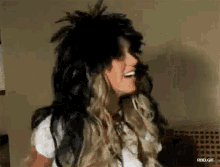 a woman wearing a wig with feathers on it is smiling ..