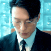 a close up of a man wearing glasses and a black suit