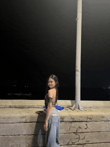 a woman in a leopard print top and jeans is standing on a wall