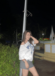 a woman wearing a white shirt with the number 5 on it is standing next to a pole
