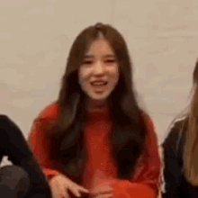 a woman in a red sweater is sitting next to another woman in a black jacket .