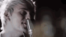 a close up of a person singing into a microphone with their eyes closed .
