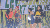 a group of young women are dancing in front of a sign that says leveling next